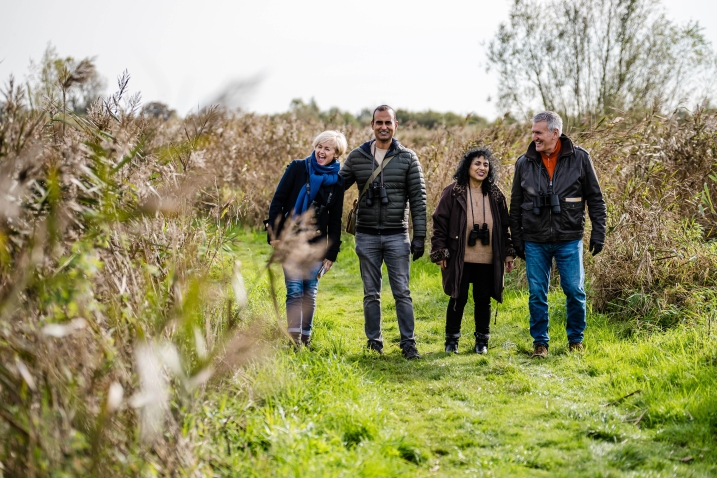 A group of four adult friends walking through the reedbed walk at WWT Martin Mere Wetland Centre.jpg